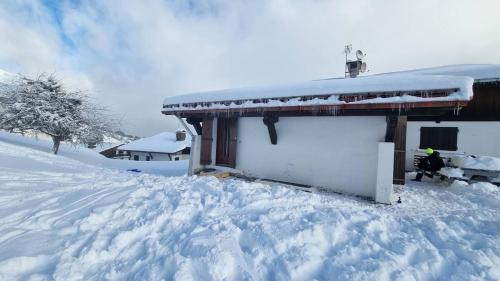 une maison recouverte de neige à côté d'un bâtiment dans l'établissement Cordon chalet appartement avec vue MontBlanc, à Cordon
