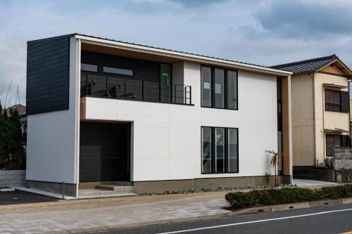 a white and black house on a street at オーシャンヴィラ館山 in Tateyama
