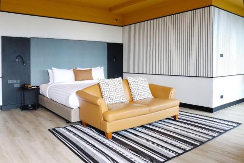 a bedroom with a bed and a couch and a chair at The Quarter Saphankhwai by UHG in Bangkok