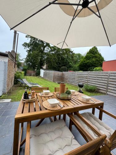 a wooden table with an umbrella on a patio at Maison proche de Pairi Daiza in Soignies