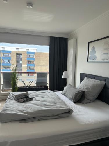 una camera da letto con un letto grande con una grande finestra di Fewo Schröder - Pier 5 - Strandkorb am Meer - seitlicher Meerblick - inklusiv Bettwäsche und Handtücher a Büsum