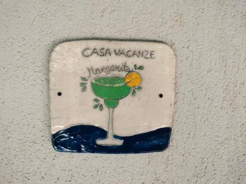 a sign on a wall with a green drink at Casa Vacanze Margarita in SantʼAlessio Siculo