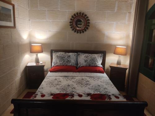 a bedroom with a bed with two lamps and a mirror at Tan-Namur Farmhouse B&B in Xewkija