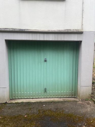 une porte de garage verte sur le côté d'un bâtiment dans l'établissement Petite maison de ville, au Mans