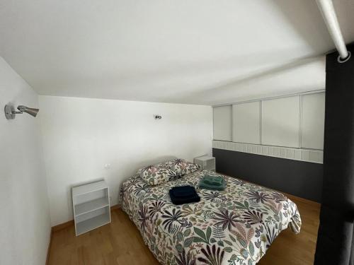 une chambre avec un lit dans une pièce blanche dans l'établissement Petite maison de ville, au Mans