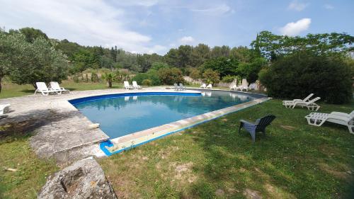 une grande piscine avec des chaises et une table dans l'établissement Villa Glycine -Mas de Joseph aux Baux de Provence, à Fontvieille