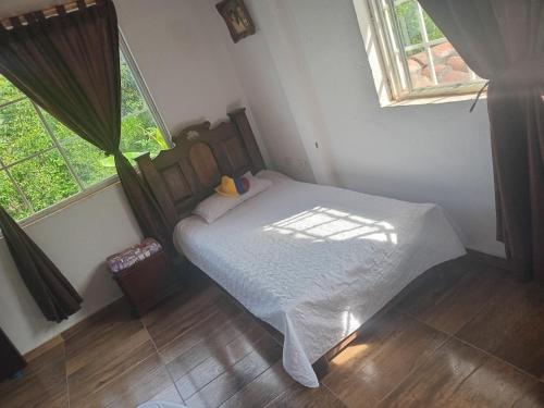 a bedroom with a bed and two windows at Trekkers haven Enjoy Colombia Ecoliving in Piedecuesta