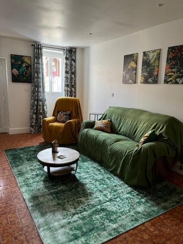 a living room with a green couch and a table at Gîte Le Grand Chêne 