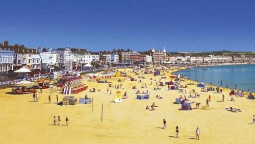 a group of people on a beach near the water at Modern Caravan 2 Bedrooms Sleeps 6 near Weymouth in Wyke Regis