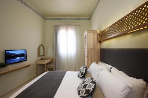 a bedroom with a large bed and a television at Dar Alma in Soûr