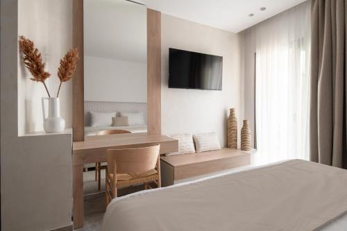 a bedroom with a bed and a desk and a television at Olenia Suites in Neos Marmaras