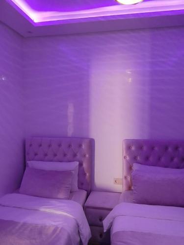 two beds in a room with purple lighting at Martil Playa Haut standing in Martil