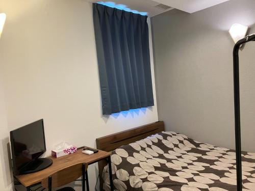 a bedroom with a bed and a desk with a television at HOTEL LEOLA - Vacation STAY 25772v in Osaka