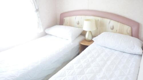 two twin beds in a bedroom with a lamp at Disabled access C10 Millfields caravan park 2 bedrooms lead person must be over 30 in Ingoldmells