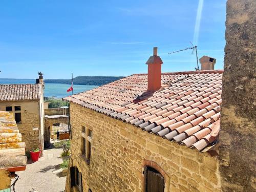 un vieux bâtiment avec un toit de tuiles avec l'océan en arrière-plan dans l'établissement Miraluna - Village médiéval, calme, insolite, 6 personnes, à Miramas