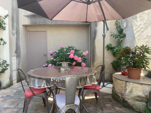 une table avec des chaises et un parasol sur une terrasse dans l'établissement Le gîte du bonheur, à Boulbon
