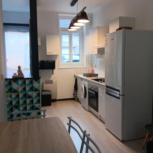 une cuisine avec une table et un réfrigérateur blanc dans l'établissement Studio meublé de tourisme, à Bourbon-Lancy