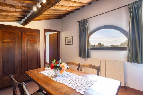 a dining room table with a vase of flowers on it at Borgo Villa Certano - Case Vacanza in Toscana in Siena