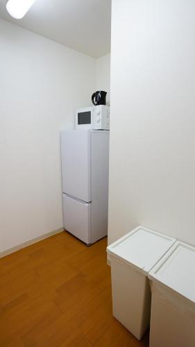 a white refrigerator in a room with a wooden floor at Helios Nakajima Park 907 Susukino Sapporo in Sapporo