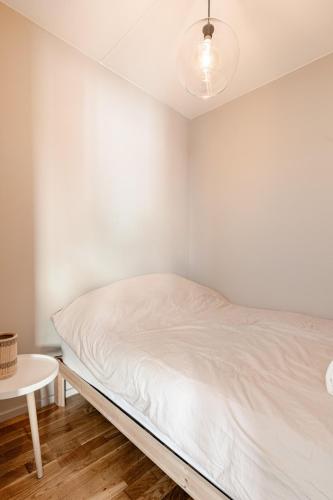 a white bedroom with a bed and a table at Spacious and super central apartment in Oslo