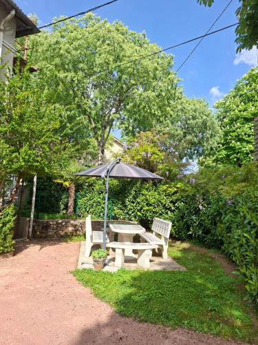 a picnic table with an umbrella and a bench at Chez Sophie et Gege. Maison de ville, deux chambres, de plain-pied in Figeac