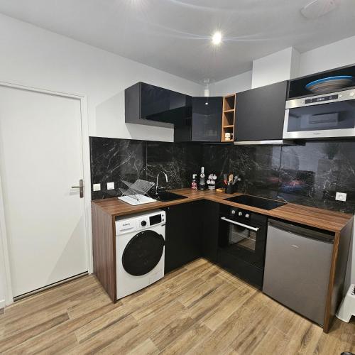 - une cuisine avec des placards noirs et blancs et un lave-vaisselle dans l'établissement Chez Francis, Avignon Centre, à Avignon