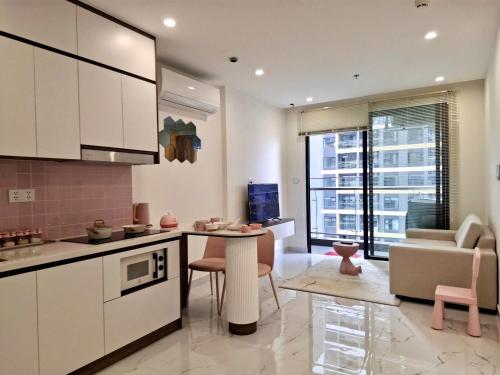 a kitchen and living room with a table and a couch at CĂN HỘ 1PN The Tropical DỄ THƯƠNG in Long Bình