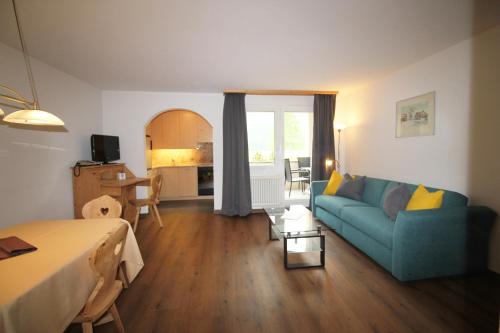 a living room with a blue couch and a kitchen at Residenza Lagrev 2 Zimmerwohnung Nr 005 - Typ 21A - Hochparterre - Süd in Sils Maria