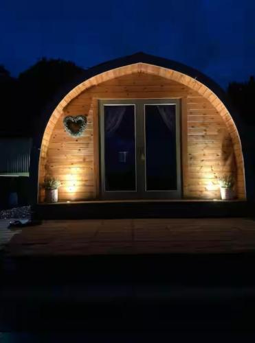 a small house with an arched window with lights at Jacob's Den Cosy pod with hot tub in Swansea