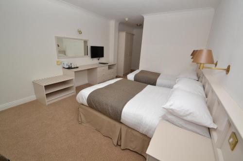 a bedroom with two beds and a desk and a television at Bay View Hotel in Killybegs
