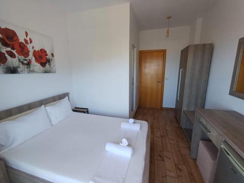 a bedroom with a white bed and a wooden door at Velco BB Himara in Himare