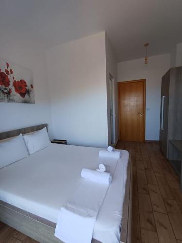 a large white bed in a room with a wooden floor at Velco BB Himara in Himare