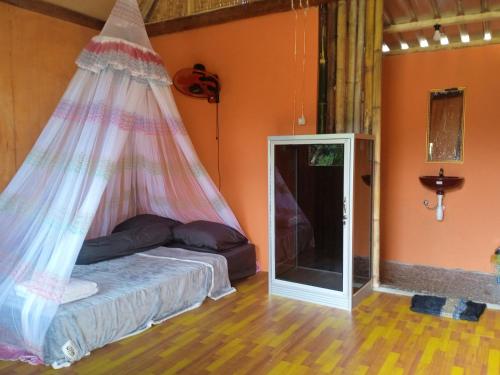 a bedroom with a bed with a mosquito net at Pondok Sedi Bungalow in Labuhancari