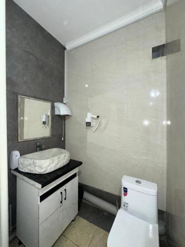 a bathroom with a white toilet and a sink at Room Hostel Tolebi in Almaty