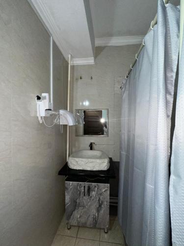 a bathroom with a sink and a shower curtain at Room Hostel Tolebi in Almaty
