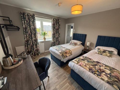ein Hotelzimmer mit zwei Betten, einem Tisch und einem Fenster in der Unterkunft Fife Arms Guest House in Keith