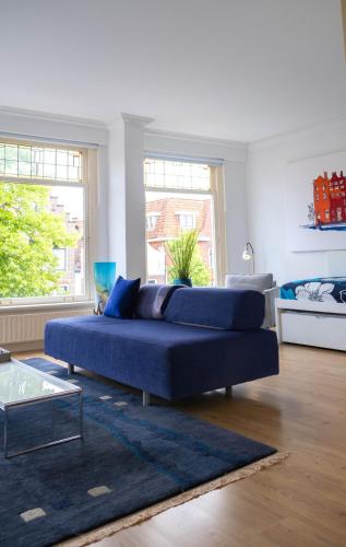a blue couch in a living room with two windows at Verdronkenoord57 in Alkmaar