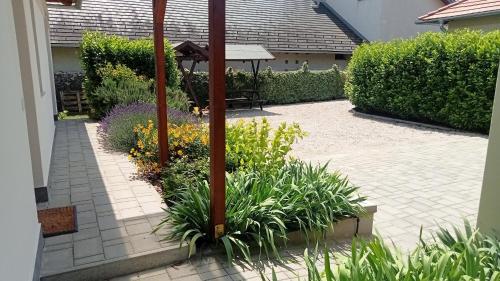 a garden with an umbrella and some plants at Bíbic Apartman D in Kápolnásnyék