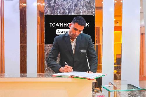 a man standing at a table signing a book at Townhouse Oak Model Town Rohtak in Rohtak