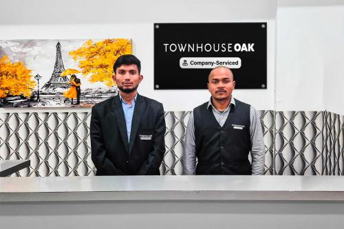 two men are standing in front of a wall at Townhouse Oak Sector 69 Gurgaon in Gurgaon