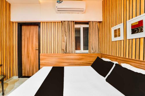 a bedroom with a black and white bed and a window at Townhouse Oak Kota Airport in Kota