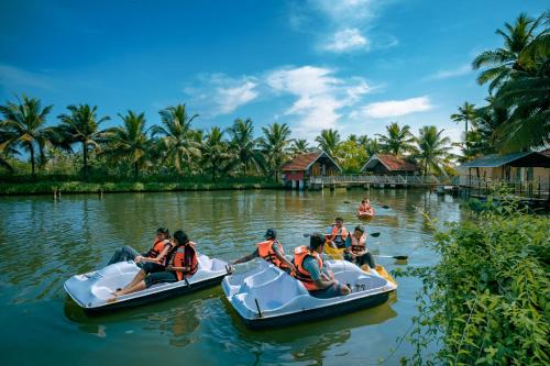 a group of people riding on inflatable boats on the water at Munroe Island Lake Resort in Kollam