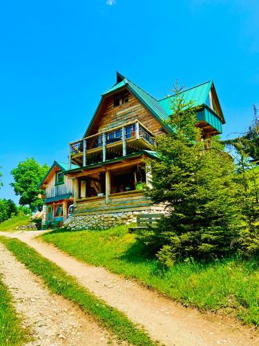 a log house on a hill with a dirt road at Mountain story apartment in Žabljak