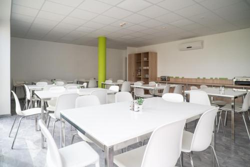 a dining room with white tables and white chairs at Skanzen Hotel in Szentendre