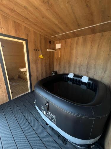 a large black tub in a room with a door at Apartament ARKON in Hermanowa