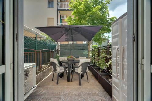 a balcony with a table and chairs and an umbrella at Ballerina Cappuccina - Patio, Netflix e Garage box in Gorizia