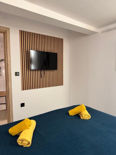 a bedroom with two yellow pillows on a blue bed at Apartman Family Aleksandrov in Néa Meságkala