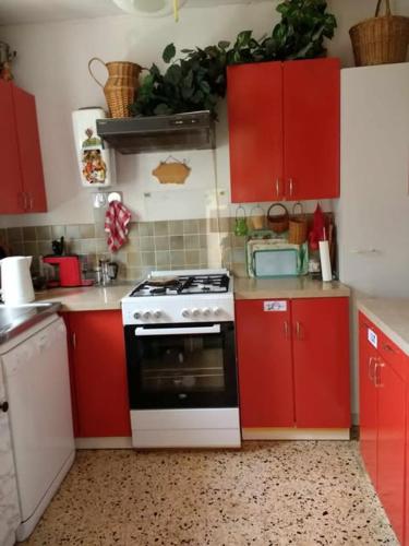 une cuisine avec des armoires rouges et une cuisinière noire et blanche dans l'établissement Dom L' Argo, à Reillanne