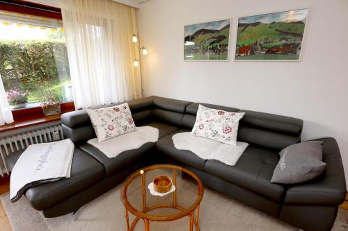 a living room with a black couch and a table at Gemütliche Fewo mit Sonnenterrasse in Bernau im Schwarzwald