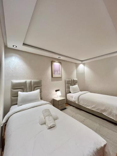 ein Schlafzimmer mit zwei Betten mit weißer Bettwäsche in der Unterkunft C1, Chic Seaside Stay at Carrousel Mall, Walk Everywhere in Rabat